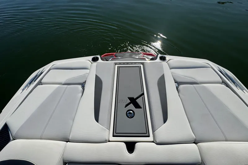 Slide: The Image of 2018 MasterCraft XStar boat's rear deck with cushioned seating and water reflection. - 23