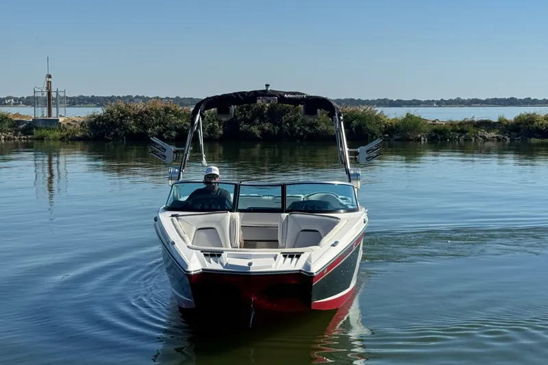 Slide: The Image of 2018 MasterCraft XStar boat on calm water, with a person at the helm. - 5