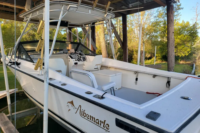 The Image of 1996 Albemarle 24 Express Cuddy Cabin boat docked under a wooden shelter. - 0