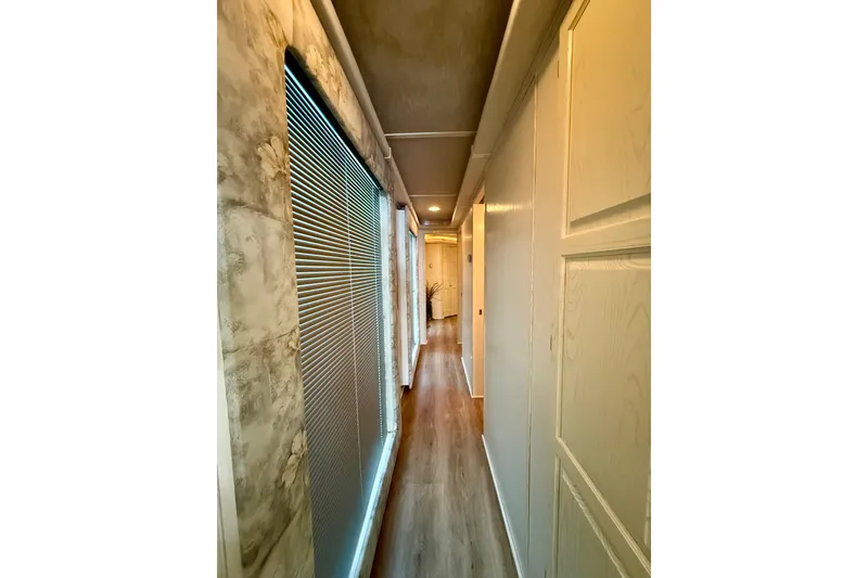 Slide: The Image of Narrow hallway inside a 2001 Fantasy houseboat with wooden flooring and modern decor. - 12