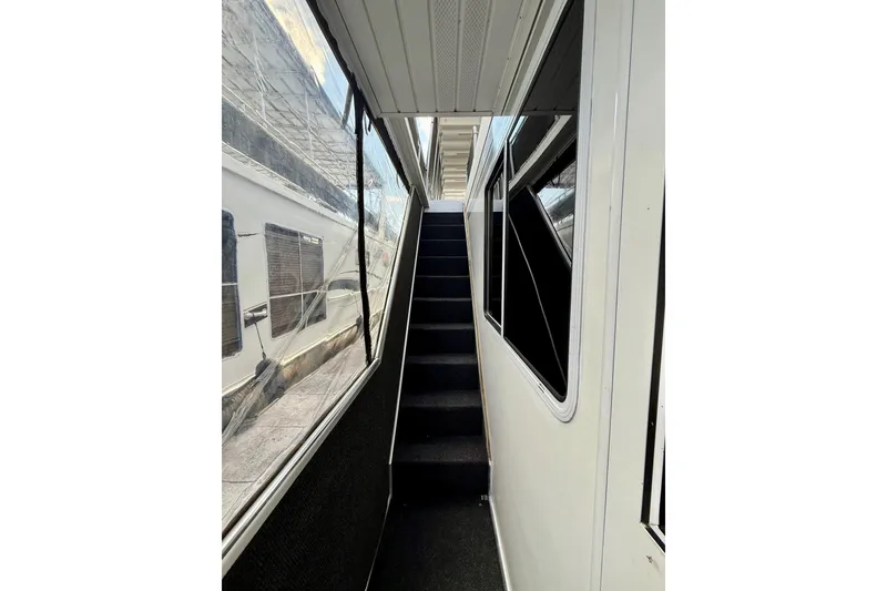 Slide: The Image of Narrow corridor with stairs inside a 2001 Fantasy houseboat, featuring large windows. - 23