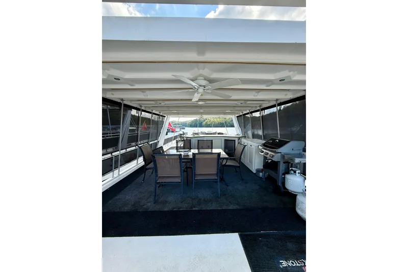 Slide: The Image of Spacious 2001 Fantasy Houseboat deck with dining area and grill, under a ceiling fan. - 27