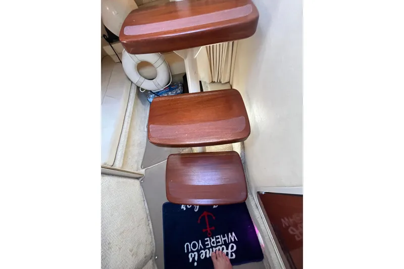 Slide: The Image of Wooden steps inside a 2002 Sea Ray 300 Sundancer boat, with a life preserver nearby. - 11