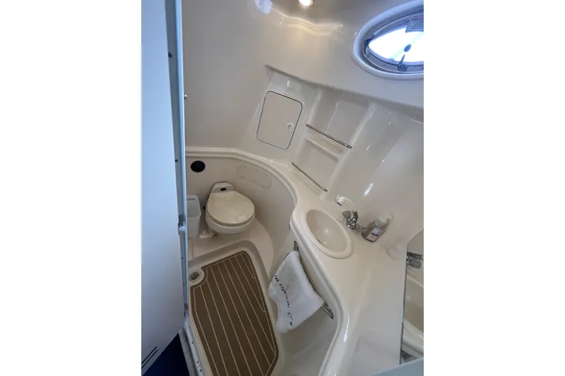 Slide: The Image of 2002 Sea Ray 300 Sundancer bathroom with toilet, sink, and porthole window. - 13