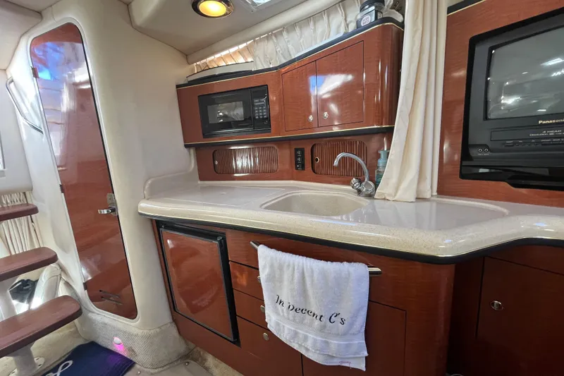 Slide: The Image of 2002 Sea Ray 300 Sundancer interior with kitchenette, microwave, sink, and TV. - 16