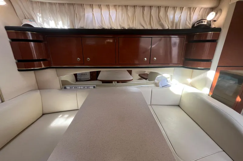 Slide: The Image of Interior of 2002 Sea Ray 300 Sundancer with white seating and wooden cabinets. - 19