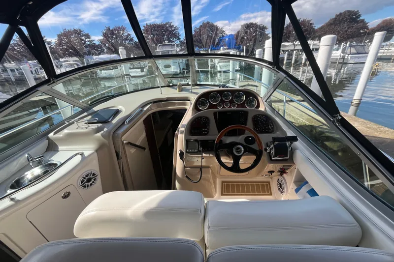 Slide: The Image of 2002 Sea Ray 300 Sundancer cockpit with steering wheel, gauges, and marina view. - 6