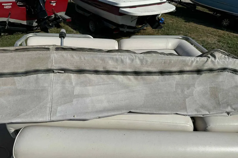 Slide: The Image of 2001 AquaPatio 240 RS boat with worn upholstery and cover, parked outdoors. - 13