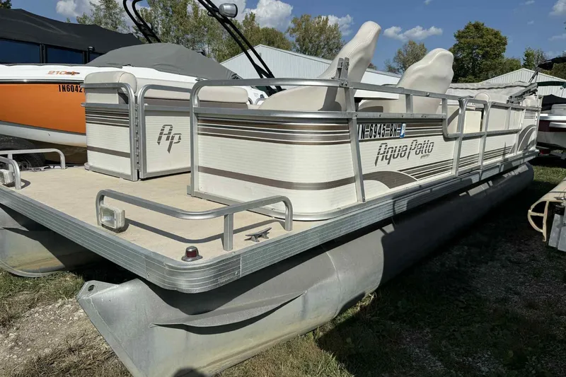 Slide: The Image of 2001 AquaPatio 240 RS pontoon boat with white seating, docked outdoors. - 2
