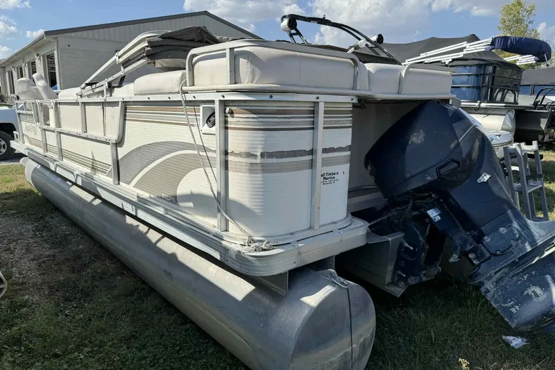 Slide: The Image of AquaPatio 240 RS 2001 pontoon boat with outboard motor, parked on grass. - 3