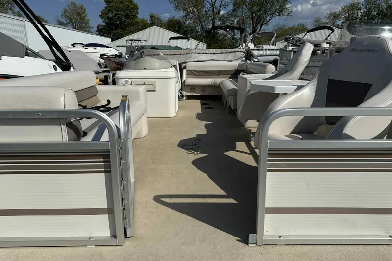 Slide: The Image of 2001 AquaPatio 240 RS pontoon boat interior with seating and helm, docked outdoors. - 6