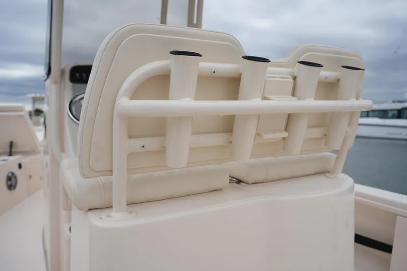 Slide: The Image of 2025 Grady-White 251 Coastal Explorer boat seating with rod holders, docked under cloudy skies. - 22
