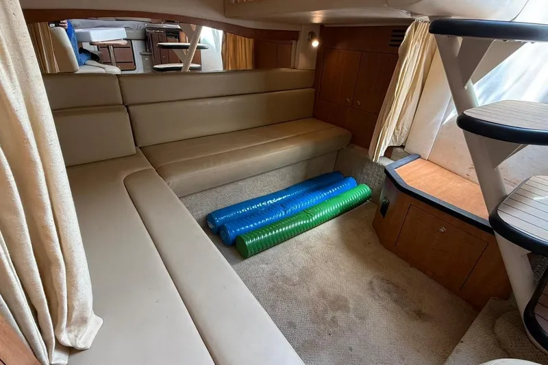 Slide: The Image of 2006 Sea Ray 340 Sundancer cabin interior with beige seating and colorful pool noodles. - 10