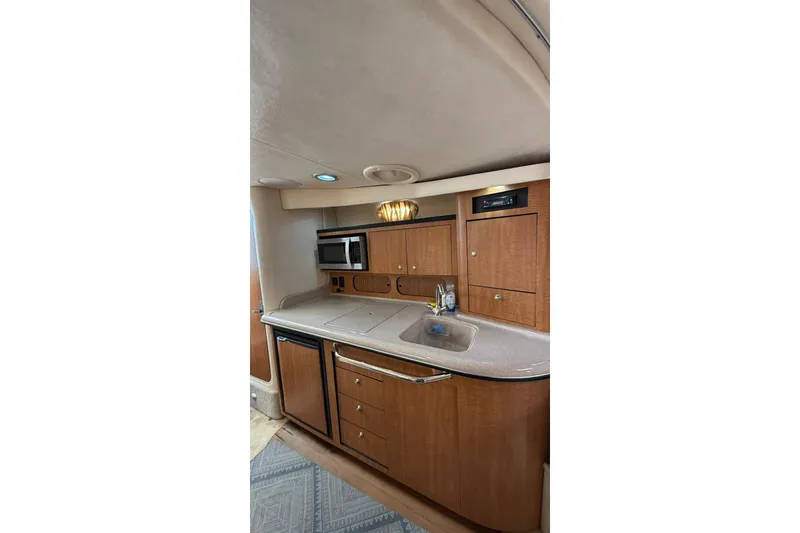 Slide: The Image of 2006 Sea Ray 340 Sundancer interior kitchen with wood cabinets, sink, and microwave. - 11