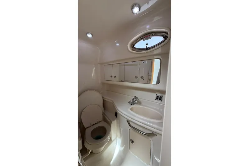 Slide: The Image of 2006 Sea Ray 340 Sundancer bathroom with toilet, sink, mirror, and porthole window. - 13
