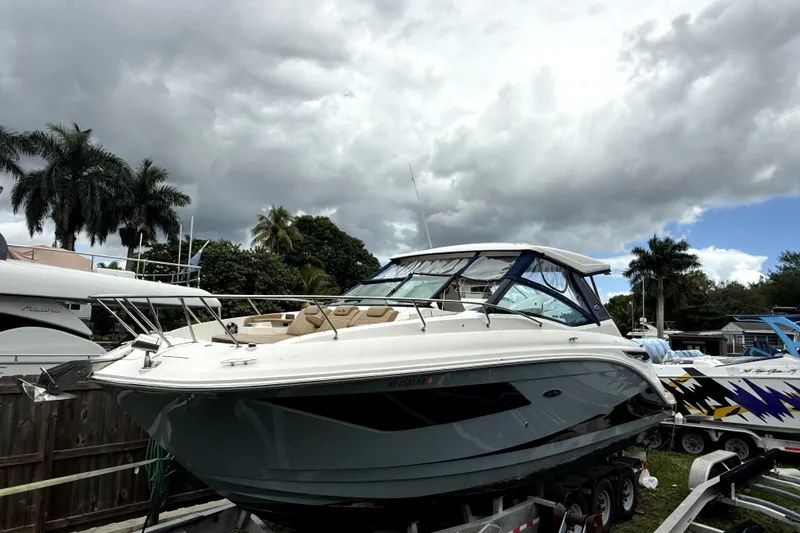The Image of 2020 Sea Ray Sundancer 320 boat on trailer, under cloudy sky with palm trees. - 0