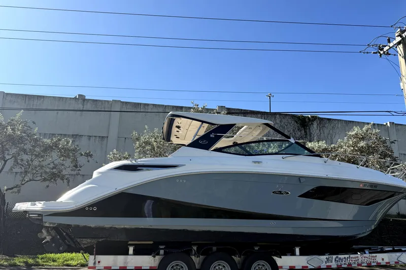 Slide: The Image of 2020 Sea Ray Sundancer 320 boat on trailer, parked outdoors under clear blue sky. - 2