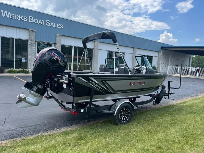 Slide: The Image of 2026 Lund 1875 Impact XS Sport boat displayed at dealership, exterior view. - 1