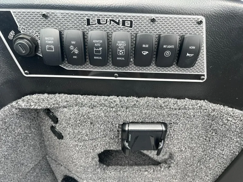 Slide: The Image of Control panel of 2026 Lund 1875 Impact XS Sport boat with various switches. - 20