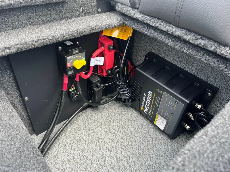 Slide: The Image of Electrical components inside 2026 Lund 1875 Impact XS Sport boat, featuring Minn Kota Precision charger. - 23