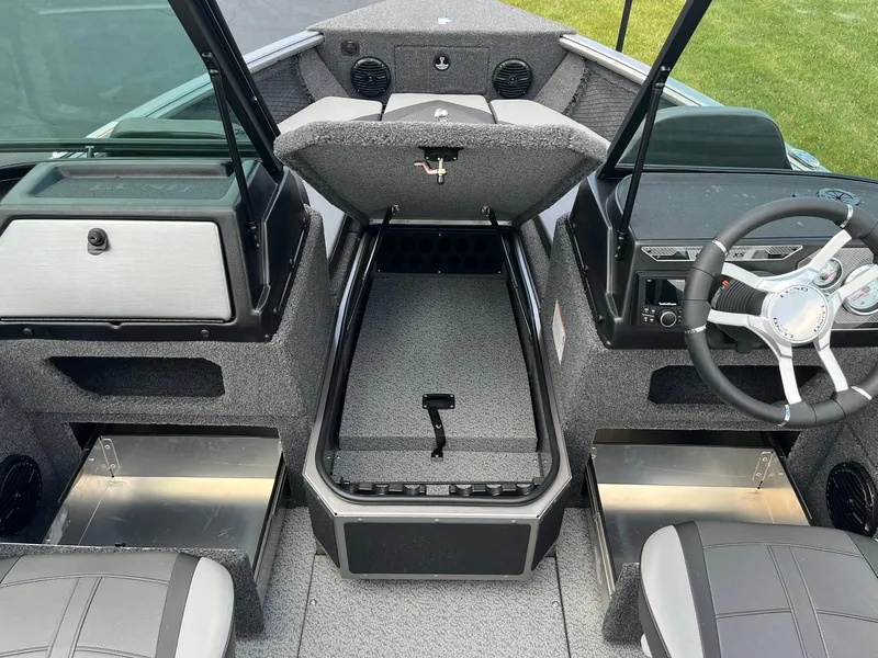 Slide: The Image of 2026 Lund 1875 Impact XS Sport boat interior with open storage compartment and steering wheel. - 9