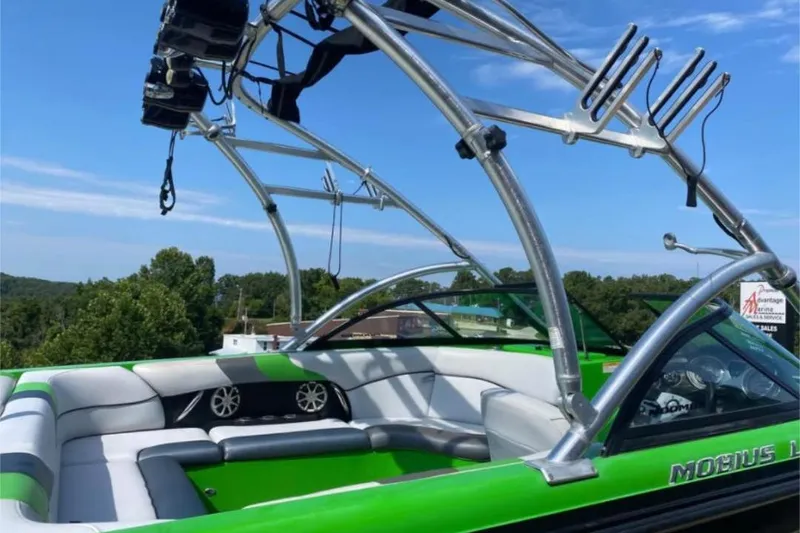 Slide: The Image of 2011 Moomba Mobius LSV boat with green and gray interior, featuring a wakeboard tower. - 2