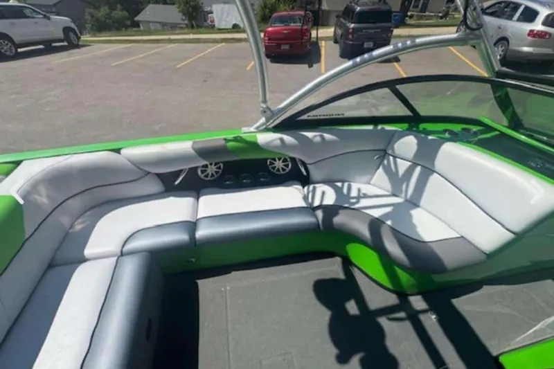 Slide: The Image of 2011 Moomba Mobius LSV boat interior with green and white seating in a parking lot. - 5