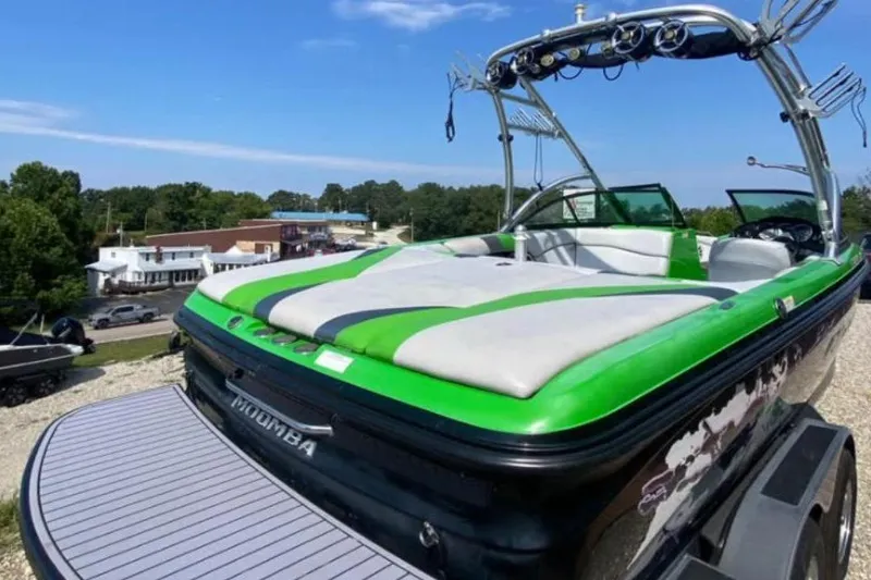 Slide: The Image of 2011 Moomba Mobius LSV boat with green accents, parked outdoors on a sunny day. - 6