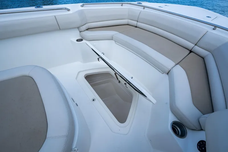 Slide: The Image of 2020 Boston Whaler 330 Outrage boat interior with cushioned seating and storage compartment. - 18