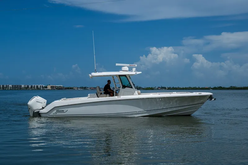 Slide: The Image of 2020 Boston Whaler 330 Outrage boat cruising on calm waters under a clear blue sky. - 2