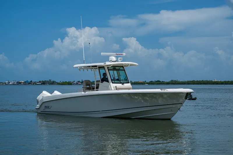 Slide: The Image of 2020 Boston Whaler 330 Outrage boat on calm water under a blue sky. - 3