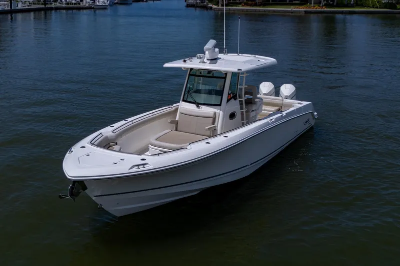Slide: The Image of 2020 Boston Whaler 330 Outrage boat on calm water, showcasing sleek design and twin engines. - 6