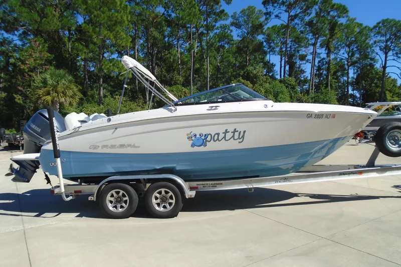 The Image of 2020 Regal LX4 boat on trailer, parked outdoors with trees in background. - 0