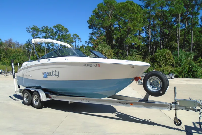 Slide: The Image of 2020 Regal LX4 boat on trailer, parked outdoors with trees in background. - 3