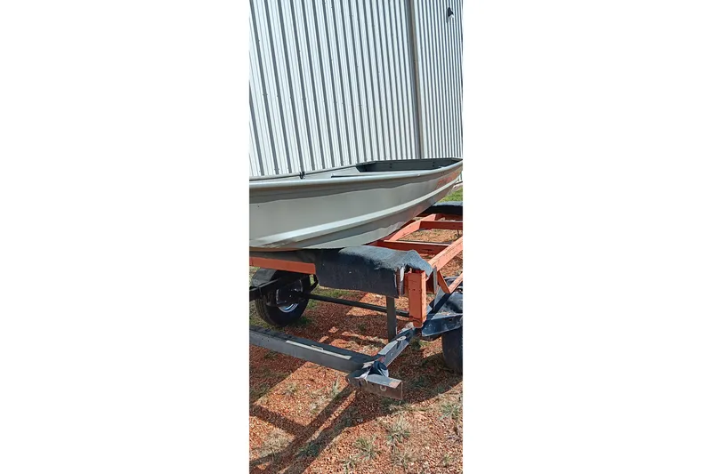 Slide: The Image of 2026 Tracker Topper 1236 boat on trailer, parked outdoors near a corrugated metal structure. - 10