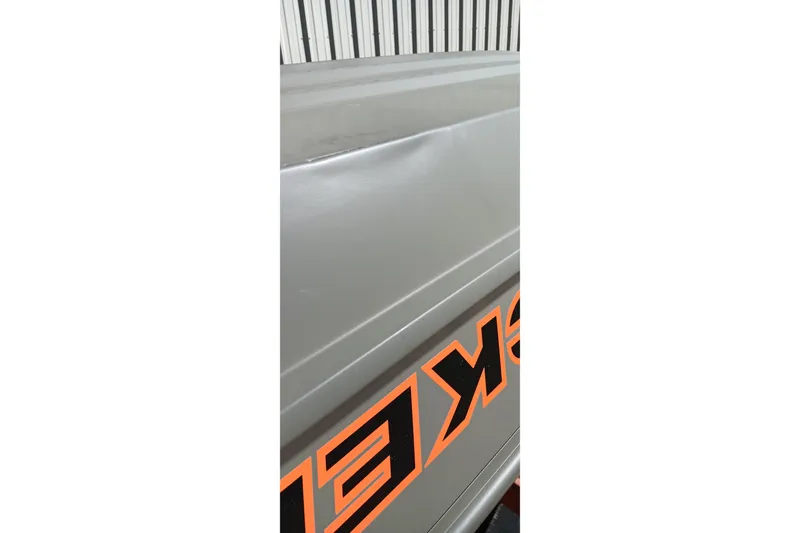 Slide: The Image of 2026 Tracker Topper 1236 boat with visible dent and orange lettering. - 13