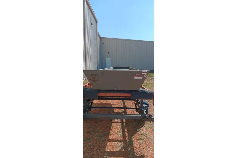 Slide: The Image of 2026 Tracker Topper 1236 boat on trailer, parked beside a building. - 16