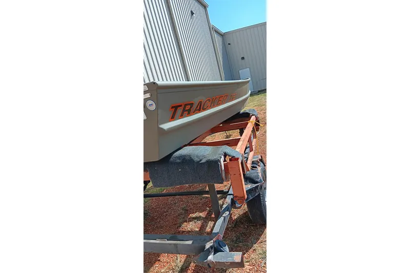 Slide: The Image of 2026 Tracker Topper 1236 boat on trailer, parked outside metal building. - 2