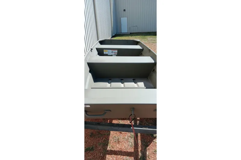 Slide: The Image of 2026 Tracker Topper 1236 boat, interior view, parked outdoors near a building. - 9