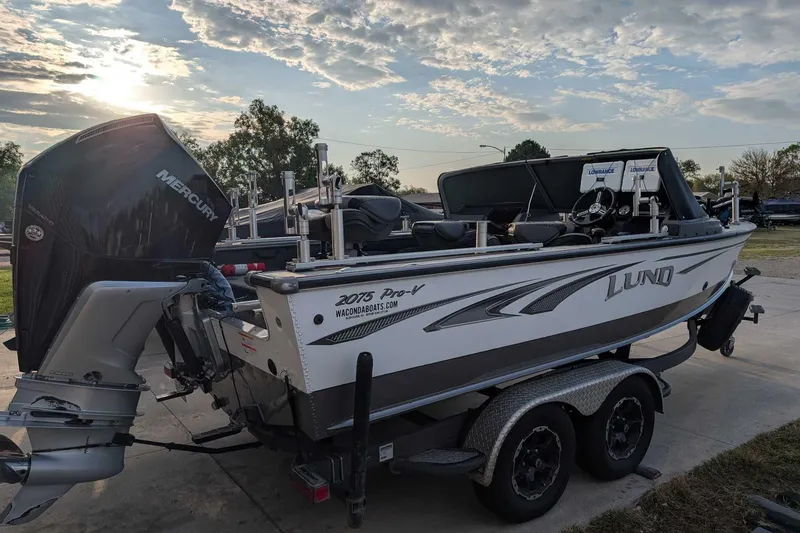 Slide: The Image of 2019 Lund 2075 Pro-V boat on trailer, with Mercury outboard motor, under a cloudy sky. - 4