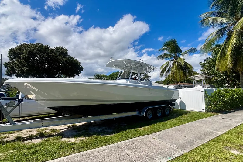 Slide: The Image of 2008 Intrepid 327 Center Console boat on trailer, surrounded by palm trees and blue sky. - 2
