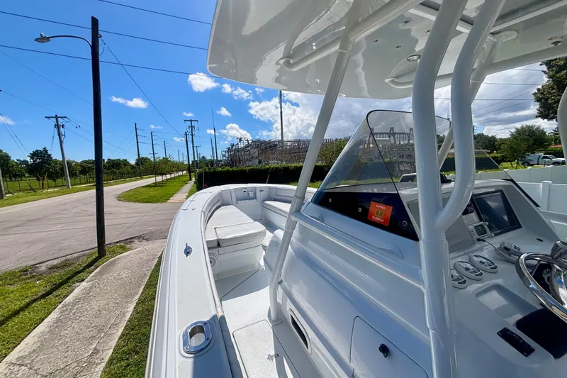 Slide: The Image of 2008 Intrepid 327 Center Console boat with sleek design, parked near a road under blue skies. - 25