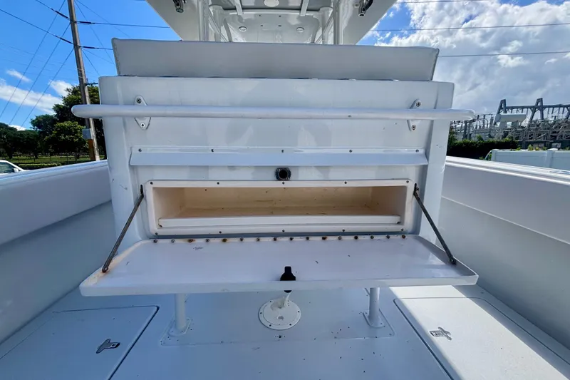 Slide: The Image of 2008 Intrepid 327 Center Console boat interior with open storage compartment under blue sky. - 38