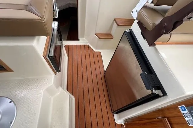 Slide: The Image of 2025 Ranger Tugs R-25 Luxury Edition interior with wood flooring and compact kitchen area. - 11