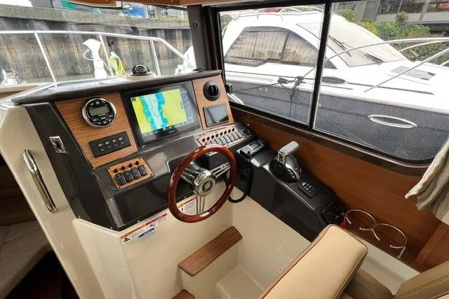 Slide: The Image of 2025 Ranger Tugs R-25 Luxury Edition helm with navigation display and wood accents. - 12