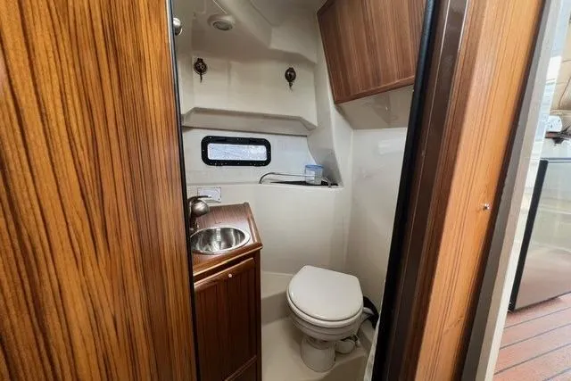 Slide: The Image of 2025 Ranger Tugs R-25 Luxury Edition bathroom with wood accents and compact design. - 16