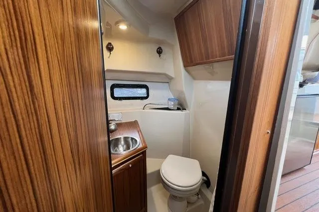 Slide: The Image of 2025 Ranger Tugs R-25 Luxury Edition bathroom with wood accents and compact design. - 17