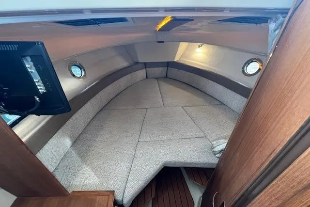 Slide: The Image of 2025 Ranger Tugs R-25 Luxury Edition cabin interior with cozy seating and elegant wood finish. - 18