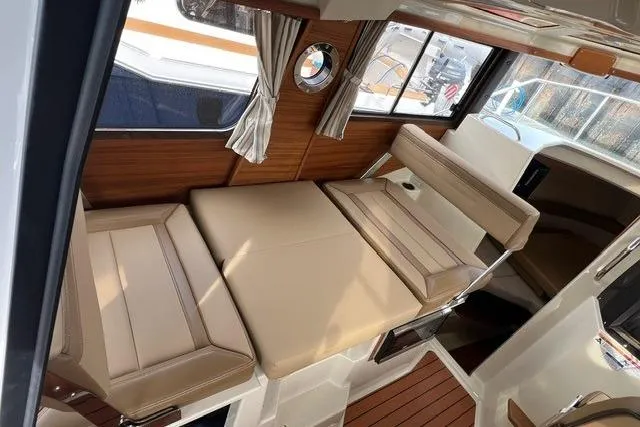 Slide: The Image of 2025 Ranger Tugs R-25 Luxury Edition interior with beige seating and wood accents. - 20