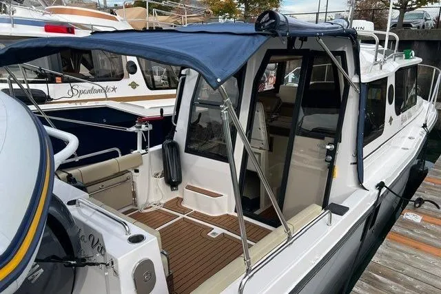 Slide: The Image of 2025 Ranger Tugs R-25 Luxury Edition boat with blue canopy, docked at marina. - 6